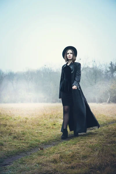 Mulher de casaco preto andando pela estrada — Fotografia de Stock