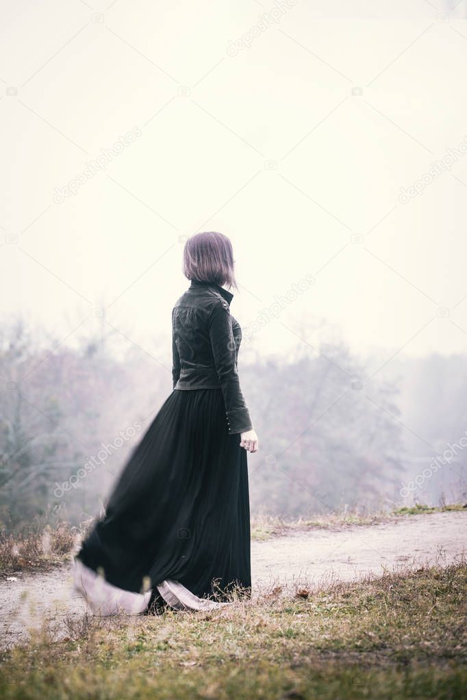 A girl walks by a cliff in windy weather
