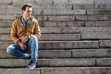 Dalgın genç adam merdivenlerde oturur