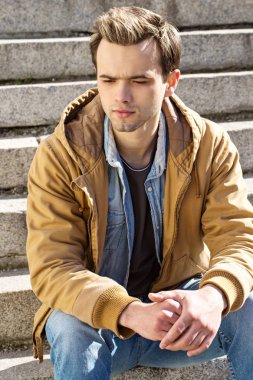 Dalgın genç adam merdivenlerde oturur