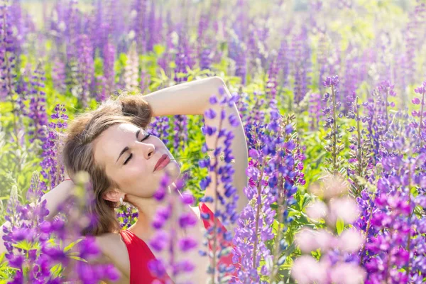 美丽的年轻女子在田野里盛开的 Lupines — 图库照片