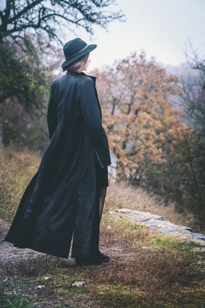 Nehrin üzerinde bir uçuruma uzun siyah bir ceket kadında