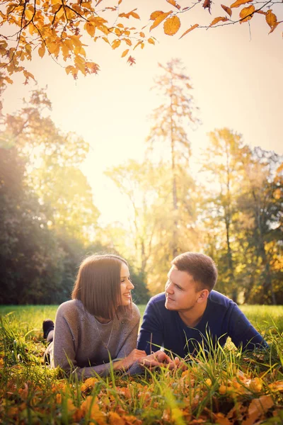 美しいカップルが秋の公園で草原に横たわっています — ストック写真