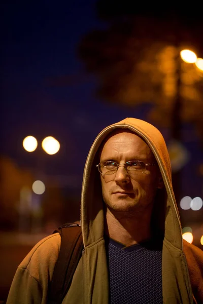 一个戴眼镜的年轻人在夜城灯光的背景下 — 图库照片