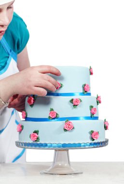 Kadın beyaz bir arka plan üzerinde izole üç katlı mavi pasta Süsle