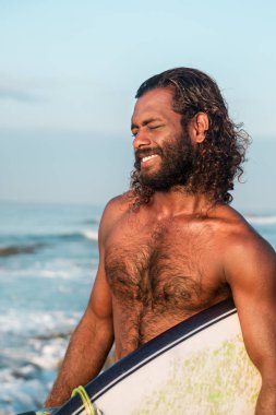 Sörfçü bir sörf tahtası Hint Okyanusu kıyısında tutuyor