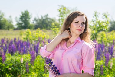 Güzel genç kadın çiçek açan lupines bir alana