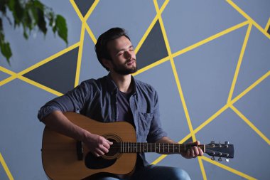 Bir sakallı bir gitar tutan genç yakışıklı adam