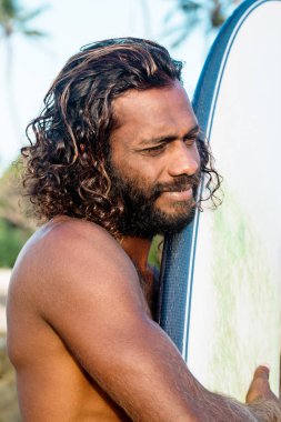 Bir genç esmer yakışıklı bir surfboard ile