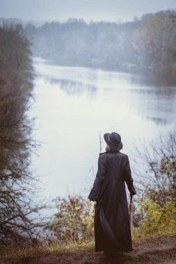 Nehrin üzerinde bir uçuruma uzun siyah bir ceket kadında