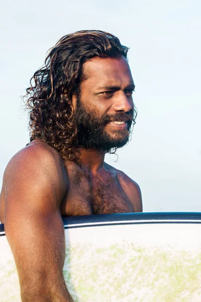 Bir genç esmer yakışıklı bir surfboard ile