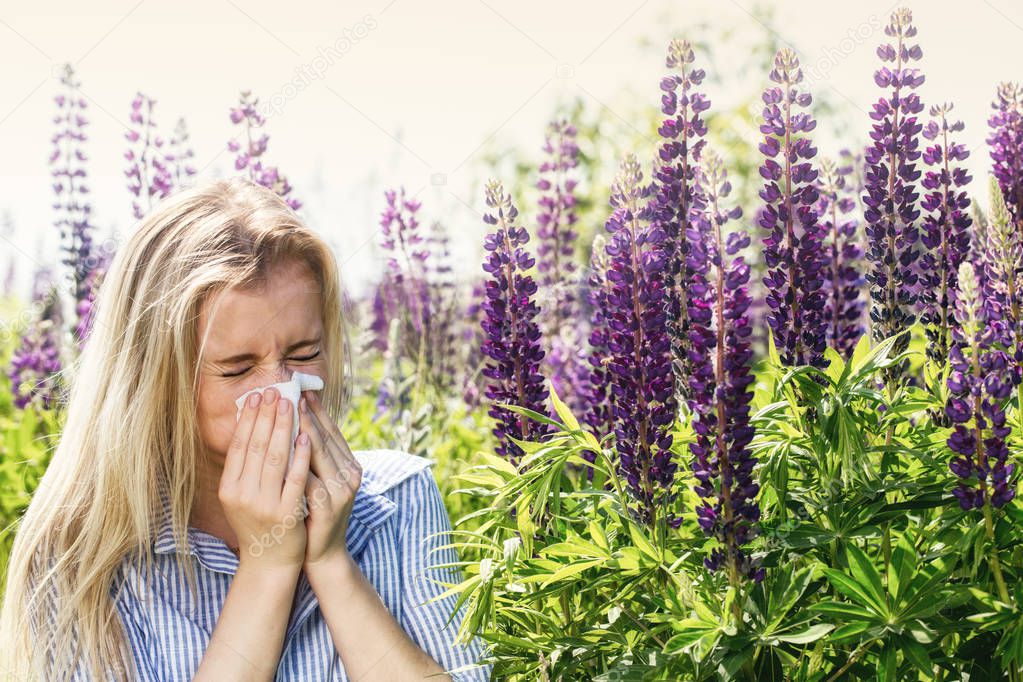 Blonde woman suffering from seasonal allergies in the meadow