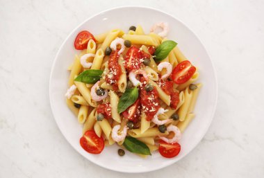 Penne alla votka makarna domates soslu karides ve beyaz bir plaka üzerinde Kapari