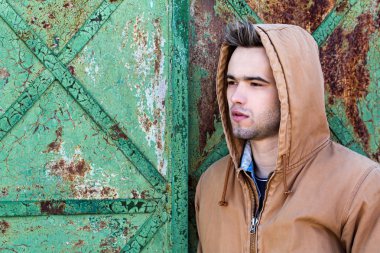 Paslı bir kapı arka plan üzerinde bir başlıklı yakışıklı bir delikanlı