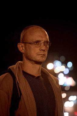 Gece şehir ışıkları arka planda gözlüklü genç bir adam