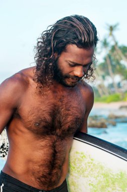 Sörfçü bir sörf tahtası Hint Okyanusu kıyısında tutuyor