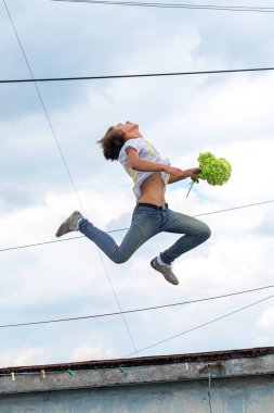 Bir bulutlu gökyüzü arka plan üzerinde atlama genç bir adam portresi