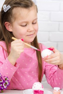 Kız Paskalya yumurtaları boya ile boyar.