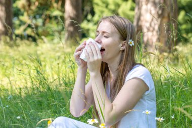 Woman in the meadow sneezes, the concept of an allergy clipart