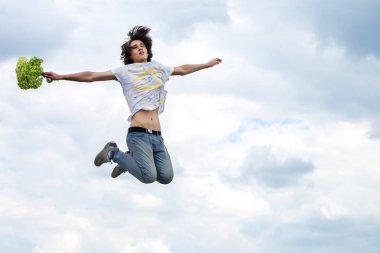 Bir bulutlu gökyüzü arka plan üzerinde atlama genç bir adam portresi