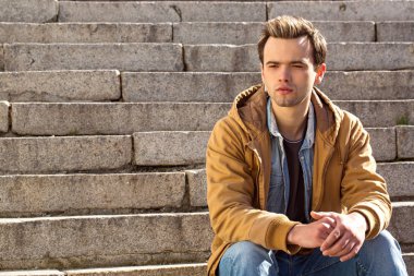 Dalgın genç adam merdivenlerde oturur
