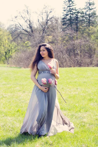 美丽的怀孕妇女在草甸与木兰分支 — 图库照片