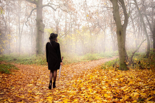 Woman in a black coat and hat in foggy weather