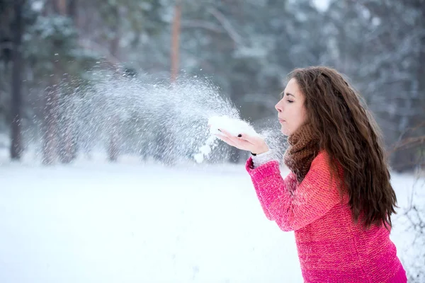 年轻美丽的女人在雪地上吹着手 — 图库照片