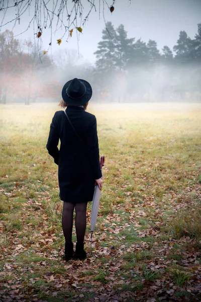Γυναίκα Ένα Μαύρο Παλτό Και Καπέλο Ομιχλώδης Καιρός — Φωτογραφία Αρχείου