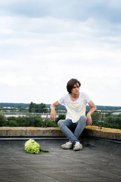 Ένας Νεαρός Άντρας Κάθεται Στη Στέγη Ένα Μπουκέτο Λουλούδια — Φωτογραφία Αρχείου
