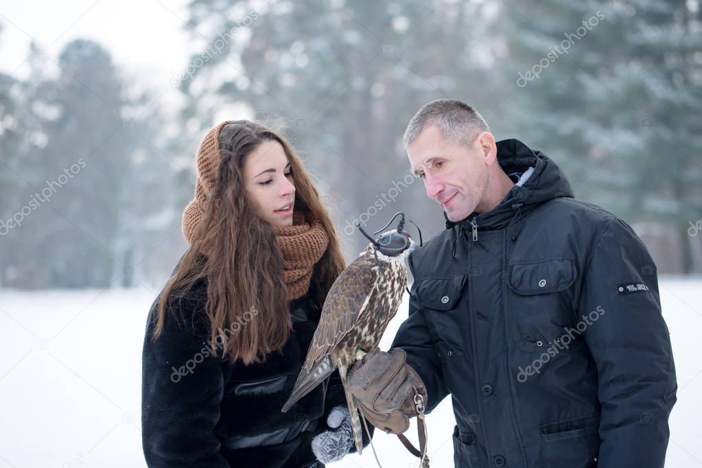 A man and a woman are holding a falcon