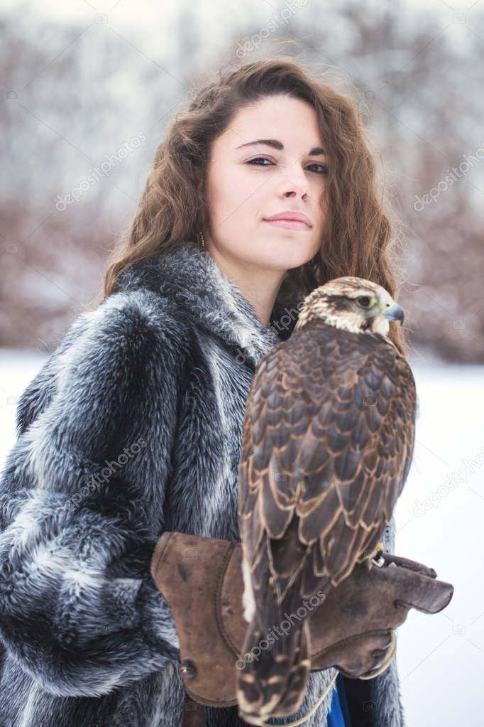 Beautiful woman holding a falcon on her hand in winter