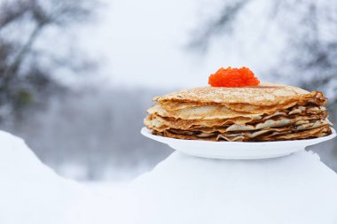 Kırmızı krep ve kış manzara arka plan üzerinde kırmızı havyar ile plaka. Kavramı kutlama için shrovetide