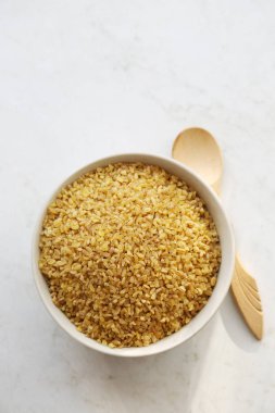 Beyaz tahta kaşıkla üzerine bir kasede Bulgur