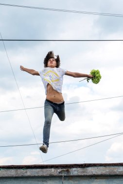 Bir bulutlu gökyüzü arka plan üzerinde atlama genç bir adam portresi