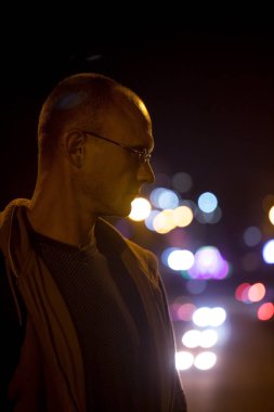 Gece şehir ışıkları arka planda gözlüklü genç bir adam