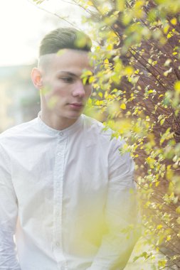 Sonbahar yaprakları ile bir çalı yakınındaki genç bir adam portresi