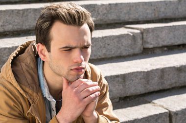 Dalgın genç adam merdivenlerde oturur