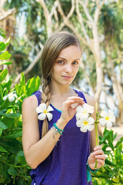 プルメリアの花のついた枝を保持している若い美しい女性 — ストック写真