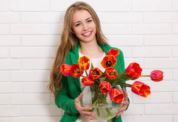 チューリップの大きな花瓶を持つ若い美しい女性 — ストック写真