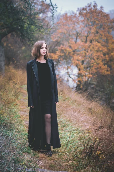 Kobieta Długi Czarny Płaszcz Nad Urwiskiem Nad Rzeką — Zdjęcie stockowe