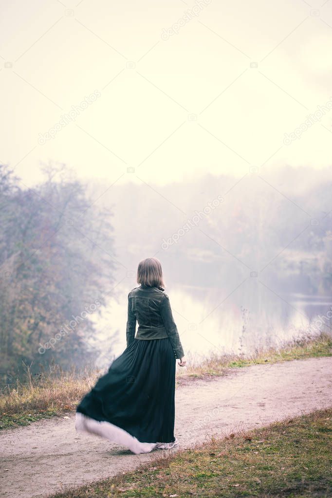 Woman in old clothes walking in foggy weather