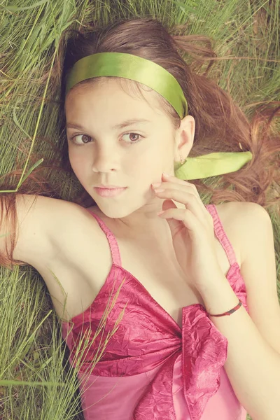 年轻女子躺在草地上的粉红色 Sarafan — 图库照片