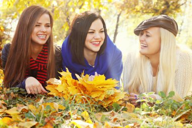 Üç güzel kız sonbahar parkta çim üzerinde yalan