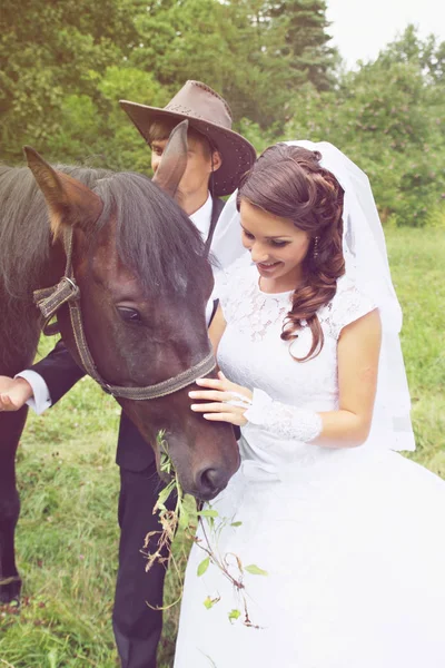 bride groom walking a horse in a field