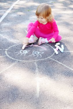 küçük kız büyük bir güneş asfalt üzerine çizer.