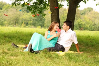 Genç çift rahatlatıcı bir ağacın altında çimlerin üzerine