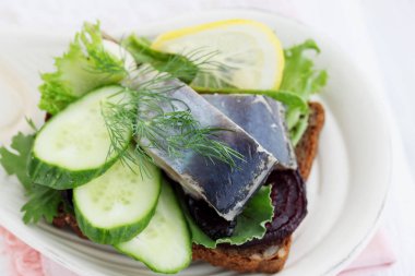 salatalık ve bir dilim ekmek üzerine limon ile ringa balığı