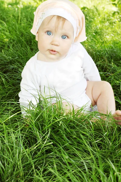 小さな女の子は新鮮な草の上に座っています — ストック写真