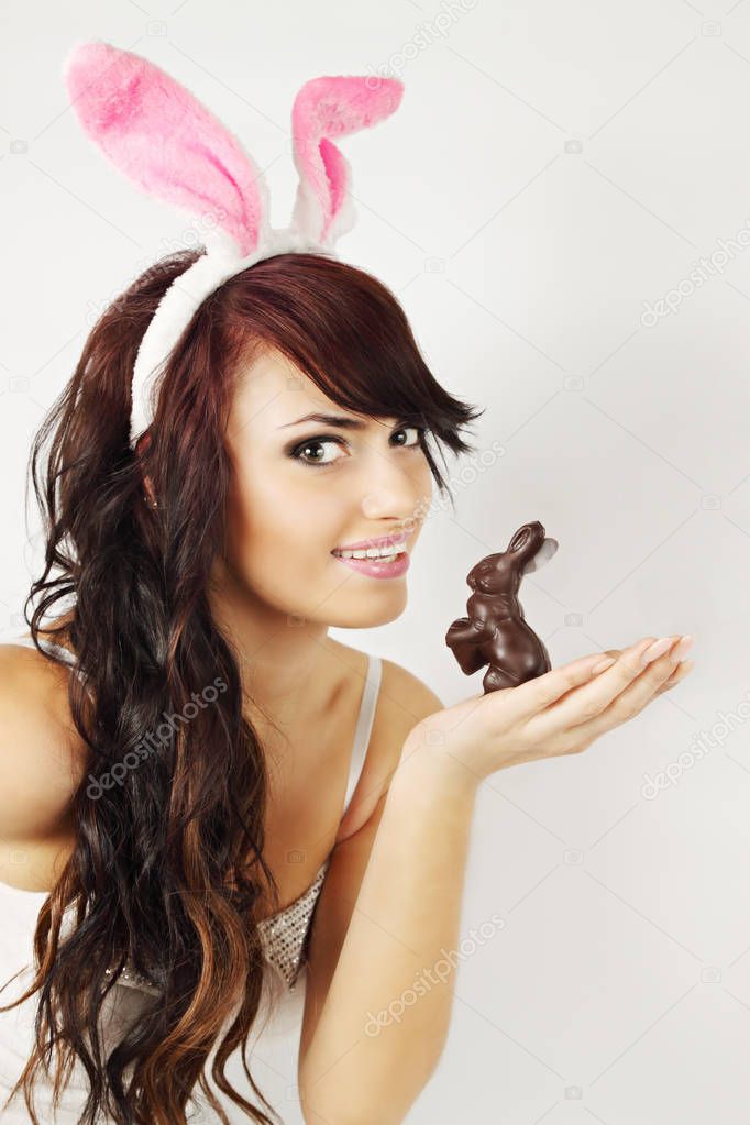 Woman in rabbit ears holds a chocolate bunny